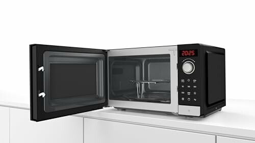 Horno microondas moderno con puerta abierta en la cocina.