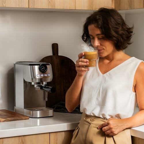 Mujer disfrutando de un café junto a una máquina de espresso.